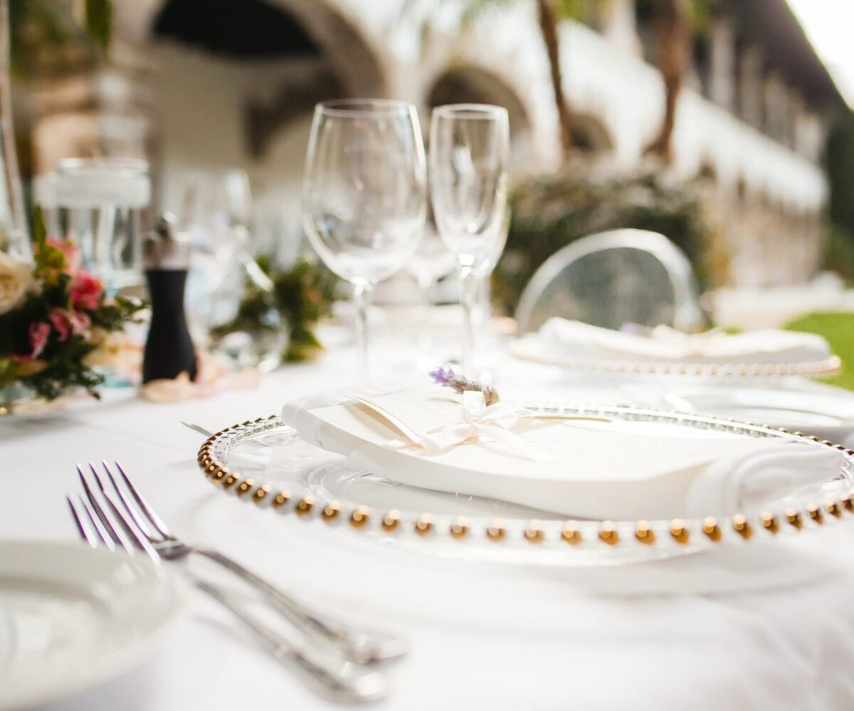 Outdoor wedding reception table setting featuring a white napkin with a lavender spring