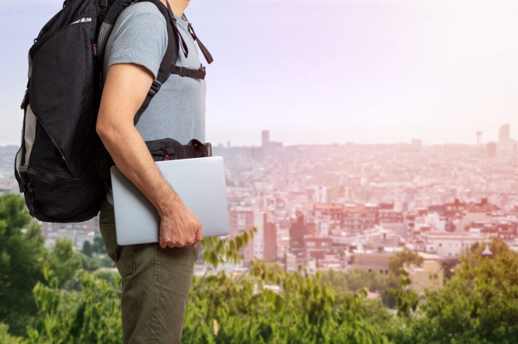 Man holding silver laptop wearing a travel laptop backpack.