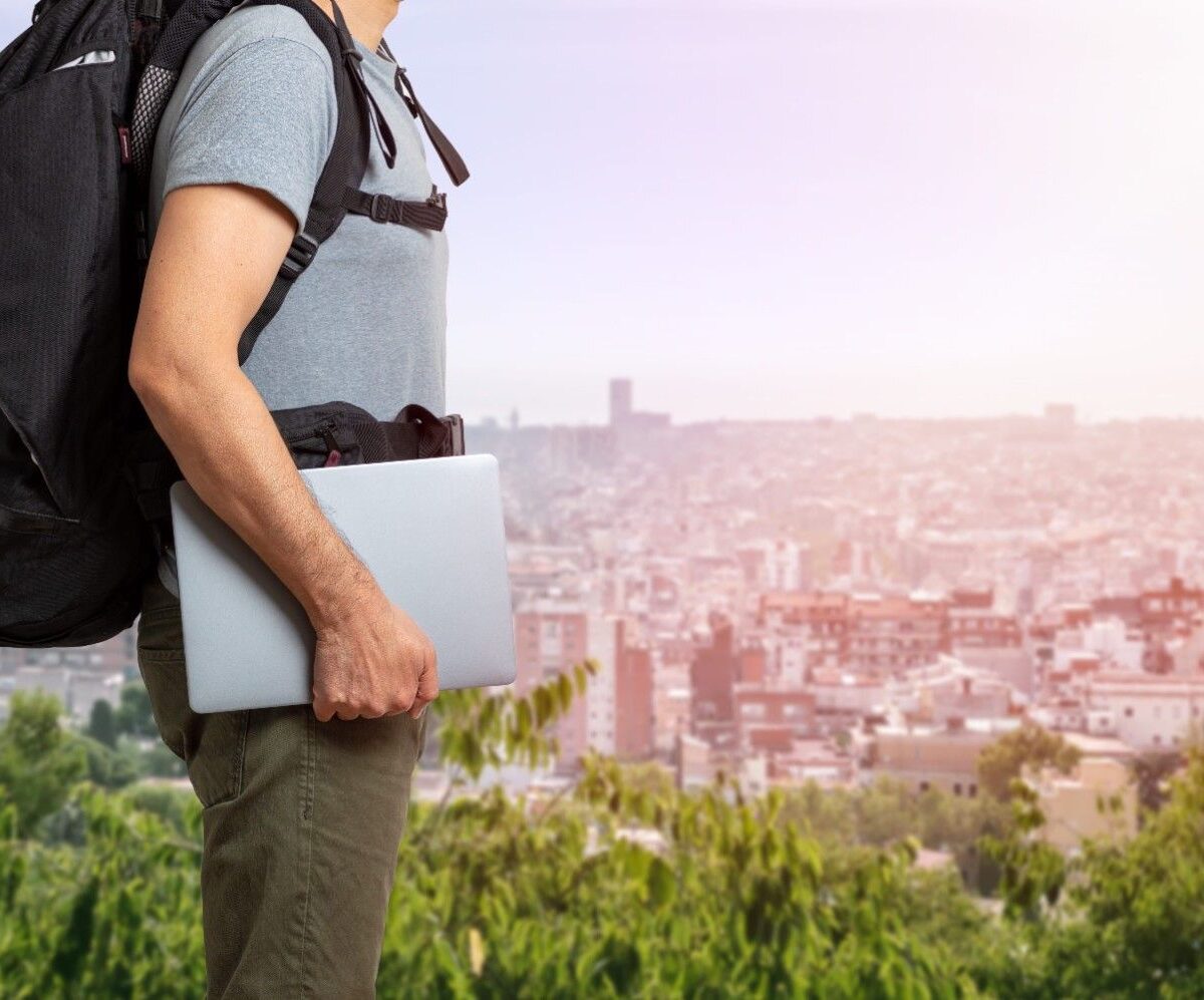 Man holding silver laptop wearing a travel laptop backpack.